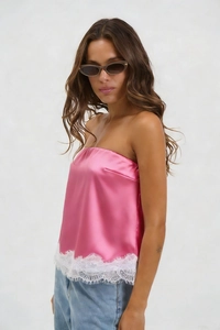 Detail of pink satin tube top featuring exquisite white eyelash lace trim at the hemline
