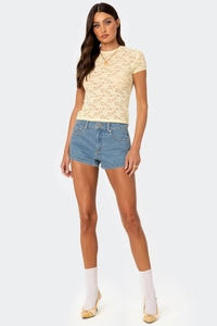 Close-up of a pale yellow lace short sleeve top featuring floral patterns and texture