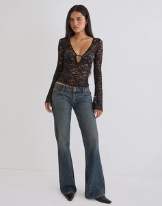 Full body view of a woman in V-neck lace long sleeve top and flare blue jeans