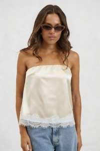 Detail of champagne satin strapless tube top featuring delicate white eyelash lace trim