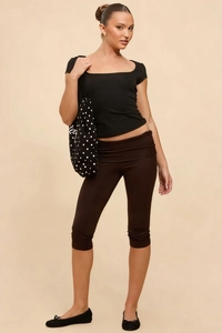Detail of trendy high-waisted capri leggings with fold-over waist and black ballet flats