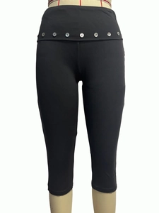 Detail of high waist black yoga capris featuring decorative silver buttons on the hip