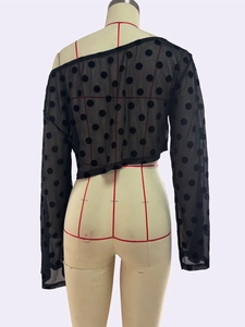 Détail d'un crop top noir en résille à pois montrant les coutures et la texture