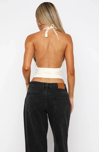 Vue de dos d'un débardeur blanc dos nu en dentelle et d'un jean en denim noir délavé