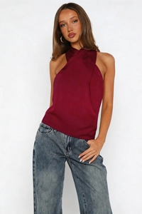 Detail of burgundy satin halter top with sleeveless design and retro blue washed denim jeans