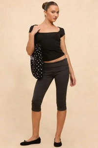 Detail of high-waisted capri leggings with fold-over waist and slim-fit black T-shirt
