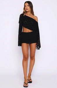 Détail d'un haut noir chic à épaule dénudée avec pois, manches évasées et short assorti