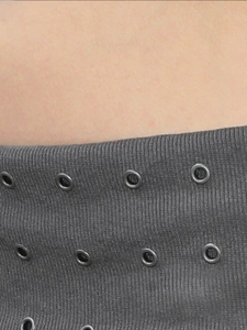 Detailaufnahme von dunkelgrauem Strickstoff mit parallelen Metallösen und Grommets