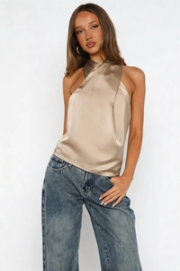 Close-up of champagne satin halter top with cross-wrap neckline and glossy texture
