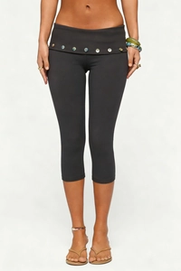 Close-up of wide fold-over waistband with decorative glossy buttons on high-waist capri leggings