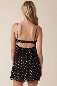 Detailed back view of a black polka dot mini dress featuring an open back and ruffle hem
