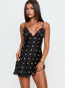 Détail de robe noire satinée à pois avec bordure en dentelle délicate au décolleté