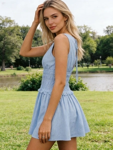Detail of light blue sleeveless mini dress featuring smocked waist and vertical striped texture