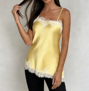 Detailed close-up of yellow satin camisole featuring delicate white lace trim on edges