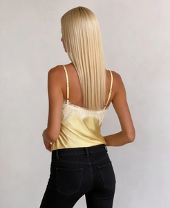 Detail of light yellow satin camisole featuring white lace trim and adjustable straps