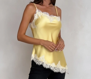 Detailed view of yellow satin camisole featuring white eyelash lace trim and asymmetric hem