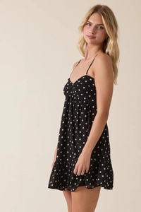 Detailed view of polka dot dress featuring a knotted V-neckline and ruffled hem detail