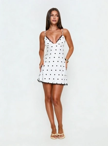 Détail d'une mini robe blanche à pois avec dentelle noire et texture satinée