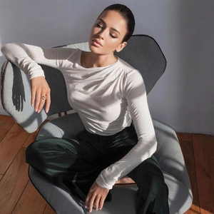 Detalle de camiseta blanca ajustada de manga larga combinada con pantalón de seda verde