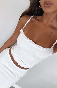 Detail van witte gesmokte crop top met ruches aan de randen en elastische textuur
