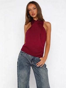 Sleeveless burgundy satin halter top for women paired with denim jeans and gold earrings