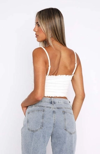 Detail van de dunne bandjes en gesmokte textuur van de witte korte camisole top