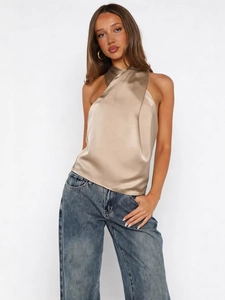 Elegant champagne satin halter top with cross-neck design paired with denim jeans