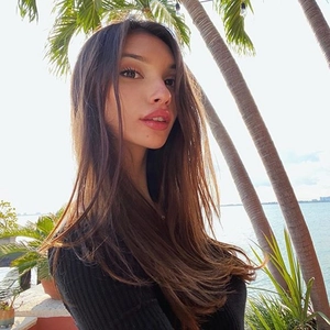 Close-up of black long sleeve bodysuit worn by model at a tropical beach setting