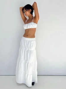 Detail of white satin two-piece set featuring a cropped camisole and layered maxi skirt
