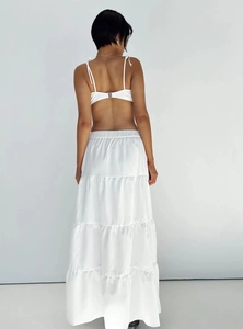 Rear view of white backless crop top and tiered maxi skirt set in smooth satin fabric