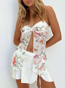 Dettaglio del crop top floreale in chiffon con spacco frontale e gonna in raso bianco