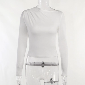 Detalle de la parte superior blanca con manga larga, cuello asimétrico y elegantes pliegues