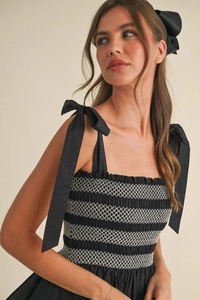 Detailed close-up of smocked bodice and shoulder tie knots on black vacation dress