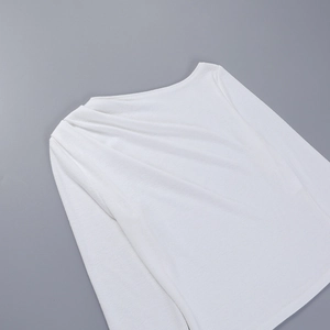 Detalle del elegante drapeado en el hombro de una camiseta blanca de manga larga ajustada