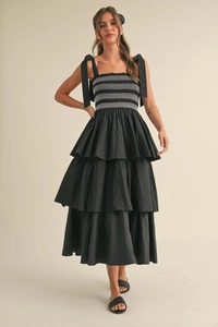 Detail of black tiered midi dress with bow tie straps and smocked bodice embroidery