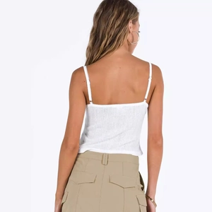 Back view of a white ribbed camisole with lace trim and slim-fit cropped design
