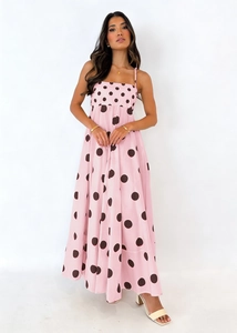 Detail of pink A-line maxi dress featuring large brown polka dots and thin straps