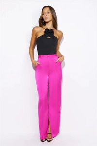Detail eines schwarzen Halter-Tops mit 3D-Stoffblume und rosa Hose mit weitem Bein