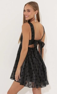 Detail of a black floral dress featuring an open back and a large decorative bow
