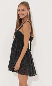 Detail view of the black floral textured fabric and oversized bow tie on the dress back