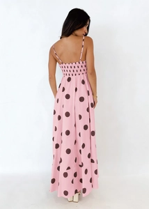 Back view of pink polka dot maxi dress featuring elastic smocked bodice and thin straps