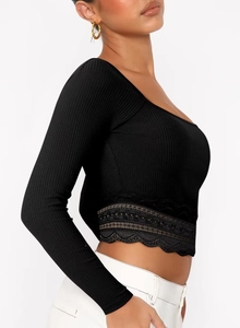 Détail du crop top noir en maille côtelée avec bordure en dentelle délicate et manches longues