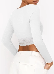 Détail du crop top blanc à manches longues avec bordure en dentelle et maille côtelée