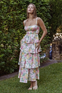Close-up of tiered floral summer dress with bow details and elegant ruffled hemline
