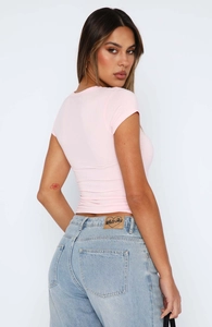 Detail view of pink slim-fit t-shirt and white fox leather patch on light blue jeans