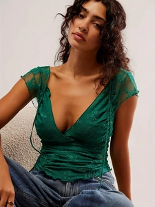 Close-up detail of emerald green floral lace fabric and V-neckline on slim fit crop top