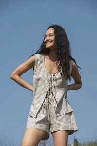 Detail of plaid cotton-linen set featuring V-neck tie-up top and shorts against blue sky