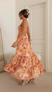 Detail of floral backless maxi dress featuring tiered skirt and halter neck design