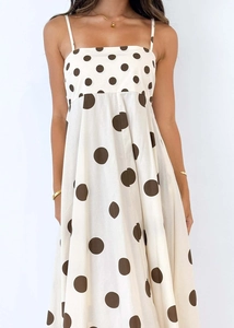 Detail of white summer dress with large brown polka dots and elegant spaghetti straps