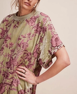 Detailed texture of olive green velvet dress with dark red floral pattern and crew neck